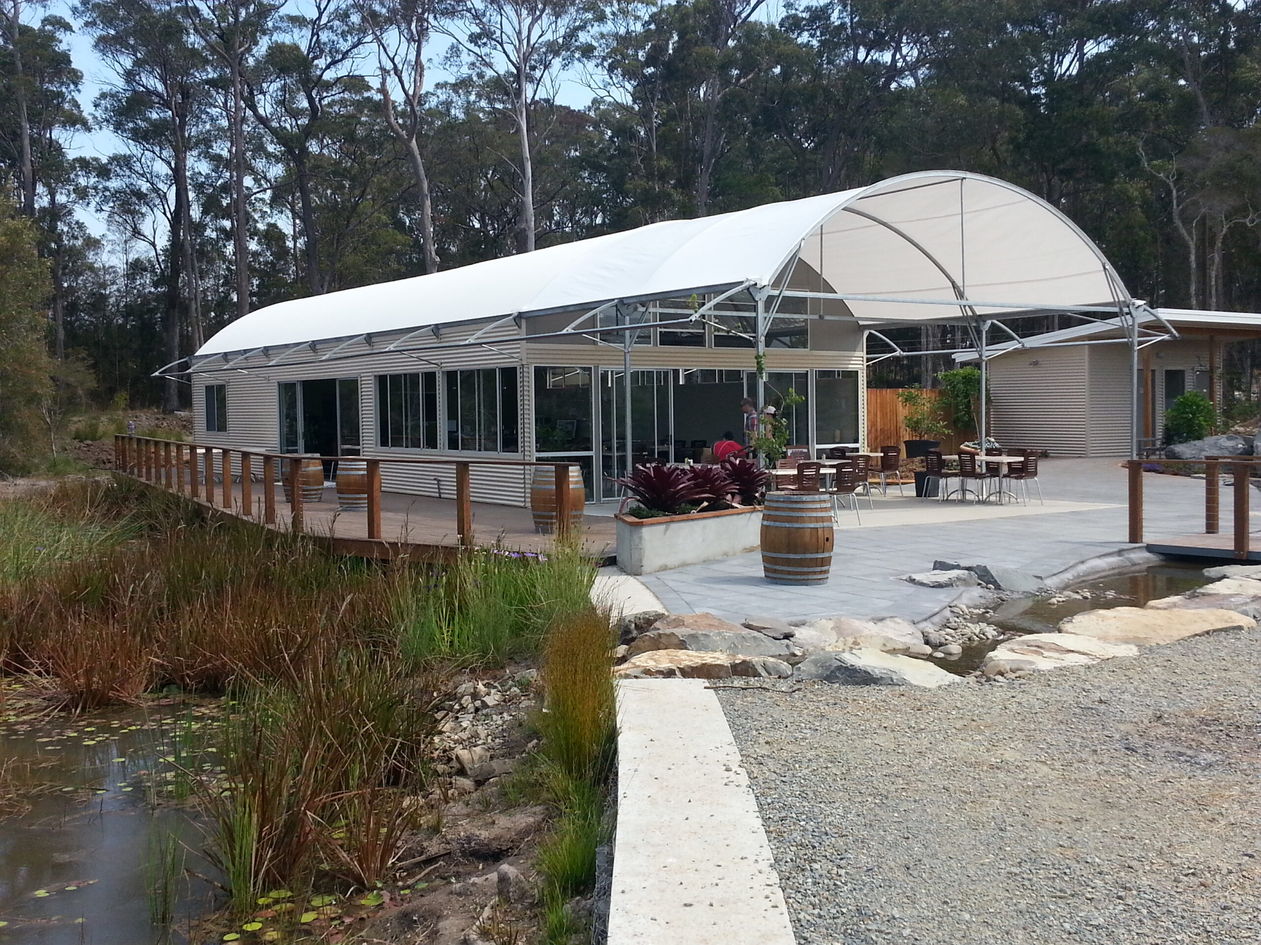 Garden Shelter structure next to a lake, with front terrace and wine barrels
