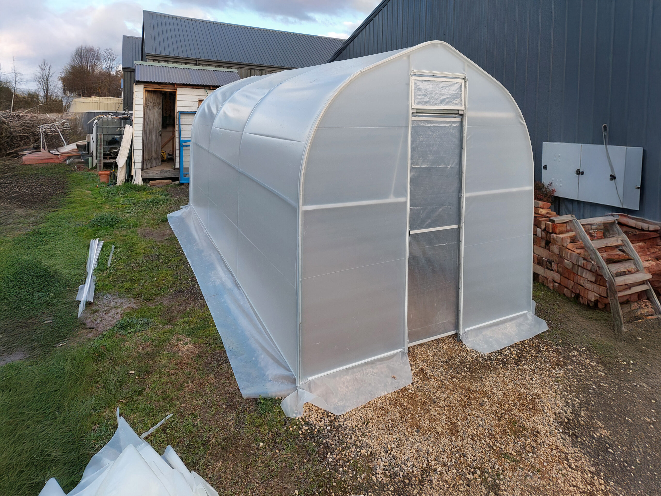 Medium sized domestic greenhouse with house in the background