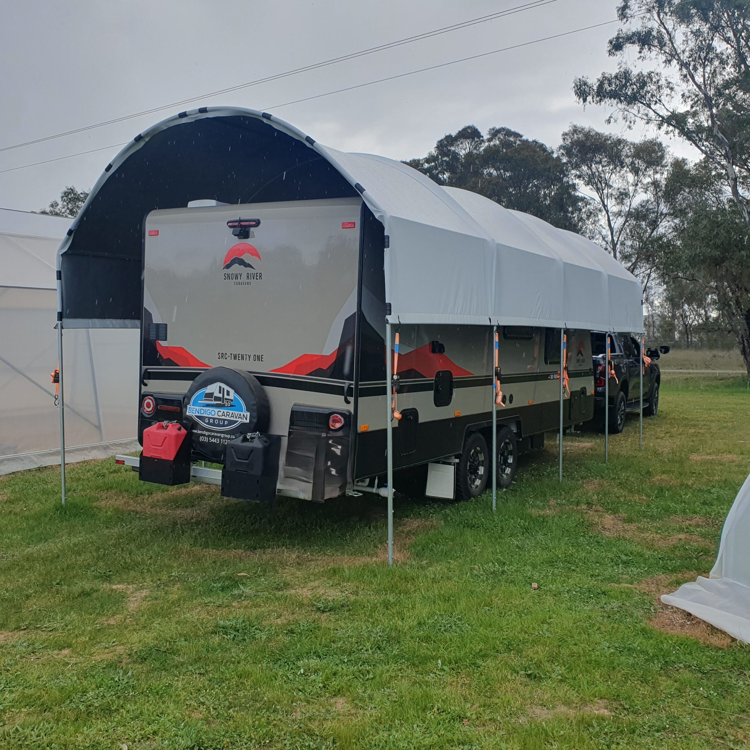 Large family caravan under a caravan shelter, on green grass