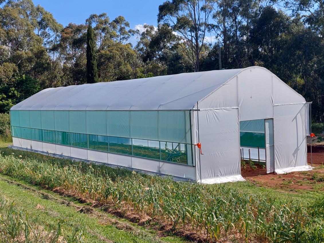Nursery greenhouse viewed from outside surrounded by grass and trees